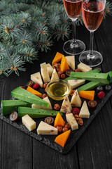 Plate with appetizer of different types of cheese, grapes and honey. Hard aged cheeses with paprika, pesto, nuts and seeds.