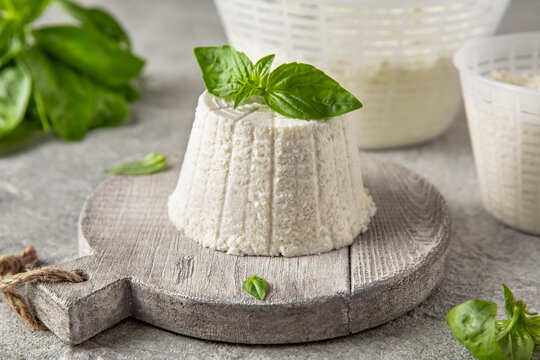 Homemade whey ricotta cheese or cottage cheese with basil ready to eat. Vegetarian healthy, nutritious diet food on a light background