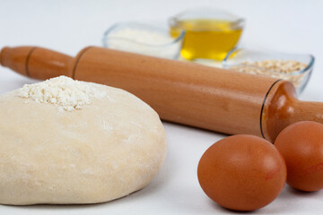 Dough with flour, olive oil, eggs and rolling pin.
