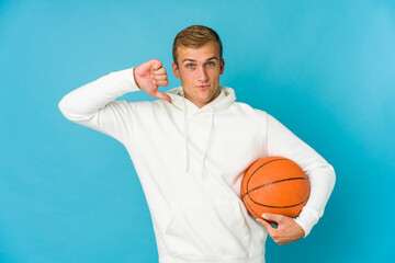 Young caucasian man playing basketball isolated on blue background