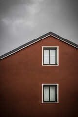 Fototapeta na wymiar Red house against dark cloudy sky