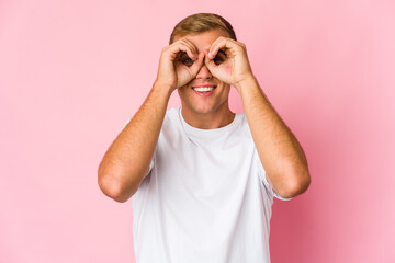 Young caucasian handsome man showing okay sign over eyes