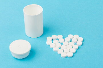 White tablets and bottle for tablets on blue background