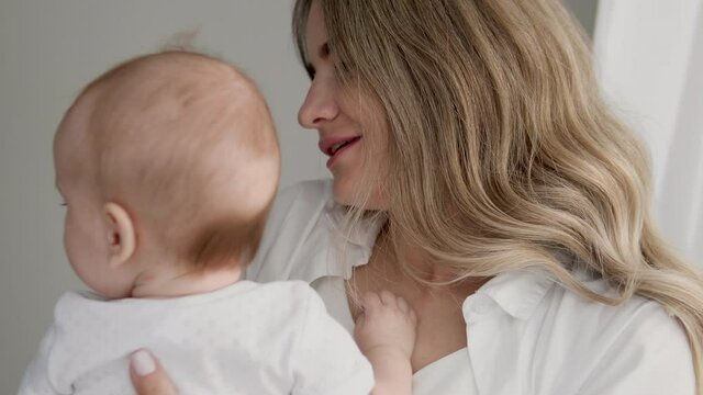 Beautiful mommy kissing her pretty tender baby, enjoying smell of little child