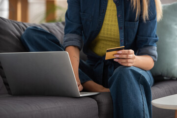 Cropped view of woman with credit card using laptop on blurred background