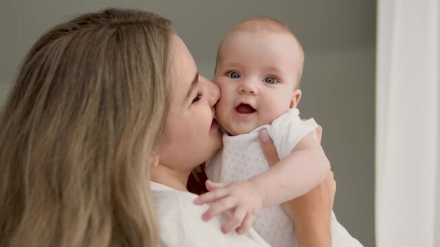 Tender pretty mommy kissing her little baby girl with cute plump cheeks, love
