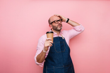 Bald mature man with hand on head and coffee in recyclable cardboard cup