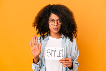 Young african american curly woman holding a smile message placard standing with outstretched hand...
