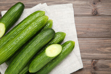 Fresh cucumbers with napkin on brown wooden background