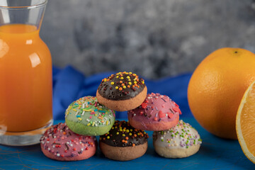 Colorful sweet doughnuts with a glass jar of juice