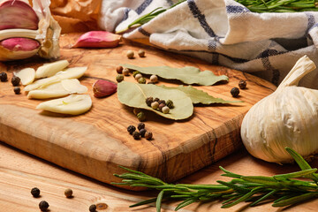Garlic, bay leaf, pepper and rosemary on a wooden background.
