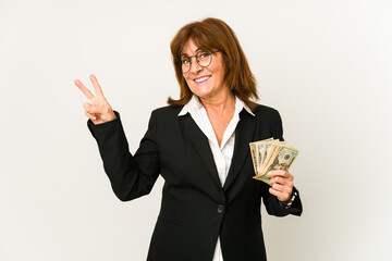 Middle age caucasian business woman holding banknotes isolated joyful and carefree showing a peace symbol with fingers.