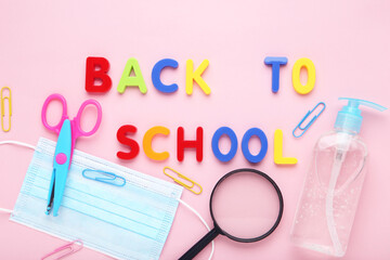 Inscription Back to School with medicine mask, sanitizer bottle and school stationery on pink background