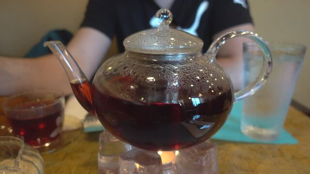 Warming up Glass Teapot with Removable Infuser with herbal black tea on the table. 