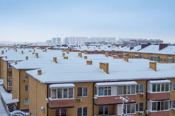 Fototapeta na wymiar Snow-covered roofs of houses in winter. City panorama, top view
