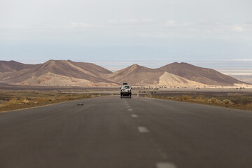asphalt in the middle of the desert on which the car is driving