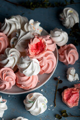 Pattern with delicate light white and pink meringue cookies on wooden background.