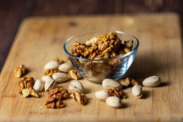 Heap of assorted nuts. a mixture of nuts in a glass plate on a wooden table, a concept of healthy food, front view