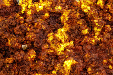 yellow and red stones in a volcanic crater that heat and boil from the heat