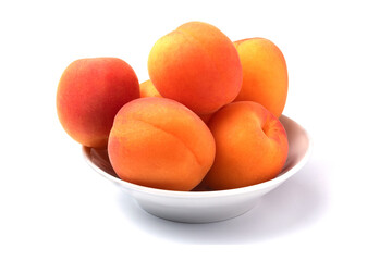 Several whole fresh juicy apricots on a plate isolated on white background with shadow.