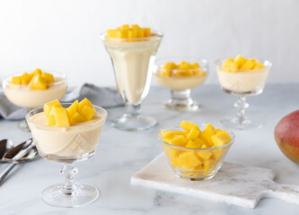 Several glass dessert dishes filled with mango mousse ready for eating.