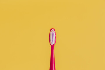 Red toothbrush on yellow background. Place for inscription
