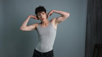 Portrait of a transgender with makeup posing on grey background. Medium shot. Masculine and feminine characteristics in one person. Gender identity concept 4k - Powered by Adobe