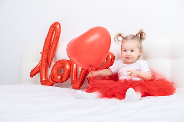cute baby girl holds the inscription love from balloons on a white background.