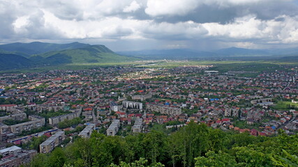 Obraz premium KHUST, UKRAINE - MAY 11, 2019. panoramic city view. view from the castle mountain and dark clouds before the storm and mountains behind on the background