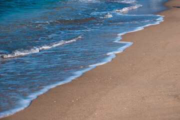 Seascape. Waves running on the sandy shore. Shore of the sea or ocean on a nice day. Vacation and relaxation by the sea.