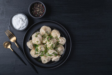 Traditional russian pelmeni, ravioli, dumplings with meat on black background. Top view. Copy space. Banner..