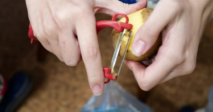 Woman peels potatoes while sitting on a chair in the kitchen
