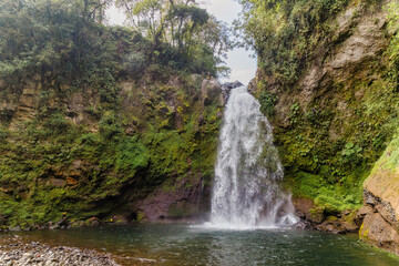 Fototapeta na wymiar A beautiful shot of a waterfall flowing through a missy rough cliff in Xico, Veracruz, Mexico