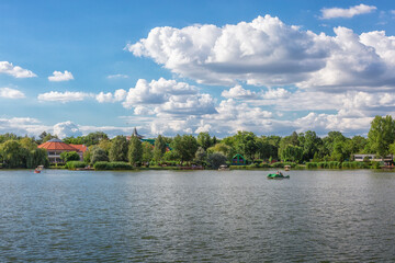 Beautiful panoramic view of landscape with lake and blue sky with white clouds. Sunny day, people relaxing, ride beach rowboats and pedal boats. Salt lake (Sosto) Nyiregyhaza, Hungary