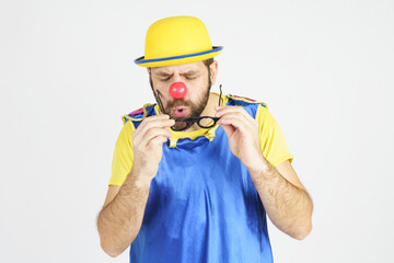 Clown in a bright blue and yellow suit cleans his glasses