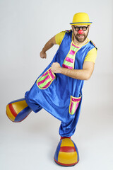 The clown is a man in a bright blue and yellow suit, glasses and a hat, playing emotionally.