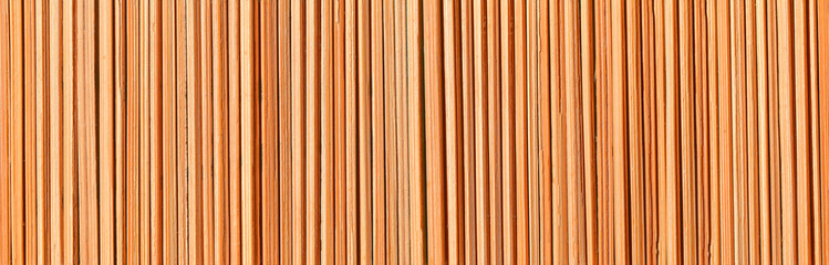 Wooden background. A texture consisting of vertical dry bamboo sticks of irregular round shape.