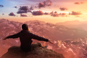 Adventurous Man with Open Hands is taking in the momen on top of a mountain. Fantasy Composite. Sunset or Sunrise Sky. Landscape from British Columbia, Canada.
