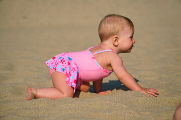 The kid learns to crawl. The child is crawling along the sand. First steps and first vacation. High quality photo