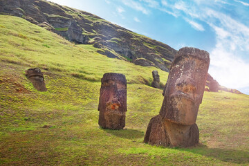 Moai on the slopes of the Rano Raraku Volcano, on Easer Island, against a blue sky covered by white clouds.