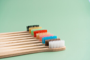 A set of Eco-friendly antibacterial toothbrushes made of bamboo wood on a light green background. Environmental care trends