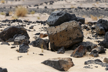dark stones in the light sand of the desert create a colored contrast