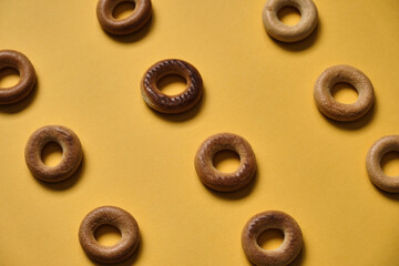 Top view of Sushki pattern on yellow surface. dish of Russian and Ukrainian cuisine, solid ring-shaped product made of dough, type of mutton products. One of the most common tea snacks among Slavs - obrazy, fototapety, plakaty