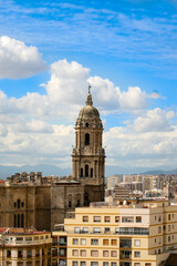 Fototapeta na wymiar A view of Malaga's skyline featuring Malaga Cathedral, with a blue cloudy sky as a backdrop. Image has copy space.