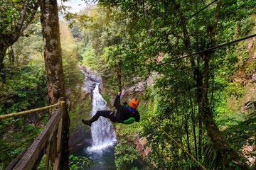 A young man riding on a zip line rope in an extreme adventure jungle in Xico, Veracruz, Mexico