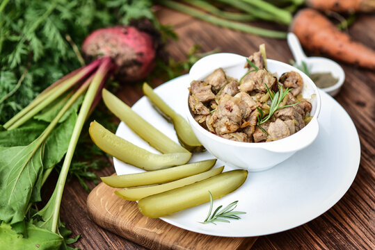 Goulash in a bowl with pickled cucumbers.