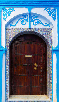 Decorated wall and door in medina of blue town Chefchaouen, Morocco. Translation: Post