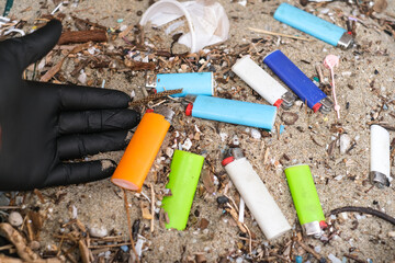 Man collecting micro plastic lighters waste on dirty ocean coast ecosystem,nature pollution