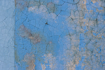 Peeling paint on the wall. Old concrete wall with cracked flaking paint. Weathered rough painted surface with patterns of cracks and peeling. Grunge texture for background and design. High resolution.
