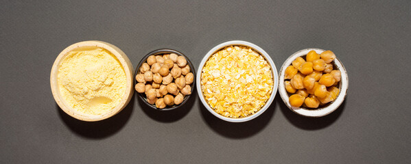 Raw and cooked chickpeas, chickpea flour and flakes in small ceramic plates, isometric projection diagonal on a black background.